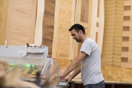 Young worker works in a factory for the production of wooden furniture