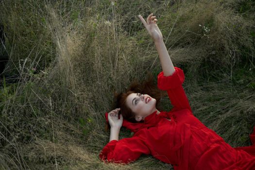 woman in red dress lies on the grass fresh air nature freedom. High quality photo