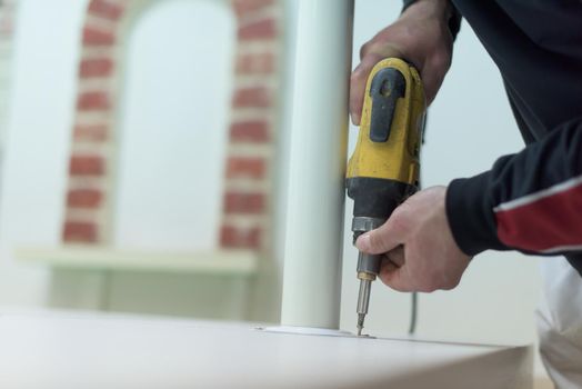 repairman working with drilling machine and assambling  furniture