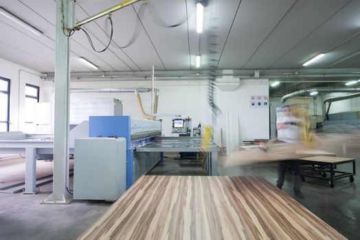 Young worker works in a factory for the production of wooden furniture