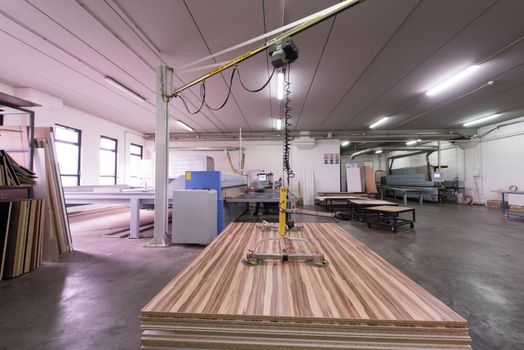 Young worker works in a factory for the production of wooden furniture