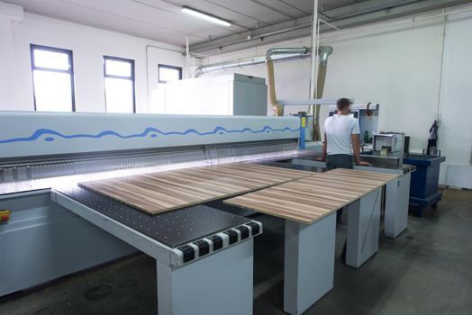 Young worker works in a factory for the production of wooden furniture