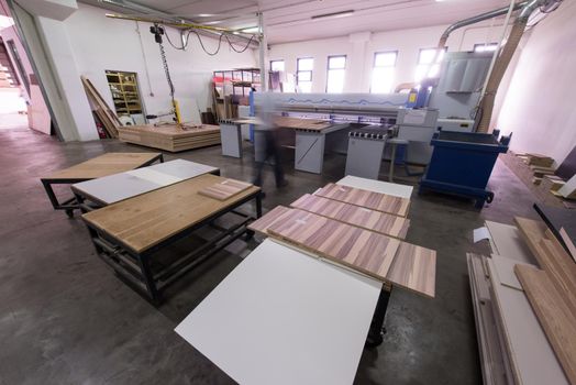 Young worker works in a factory for the production of wooden furniture