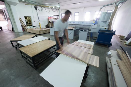 Young worker works in a factory for the production of wooden furniture