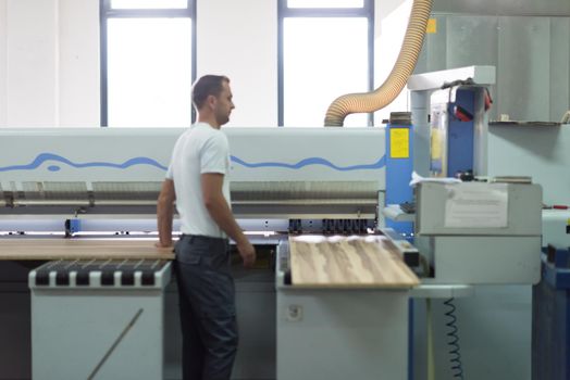 Young worker works in a factory for the production of wooden furniture