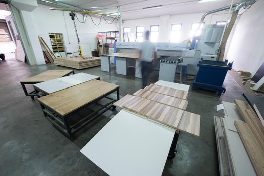 Young worker works in a factory for the production of wooden furniture