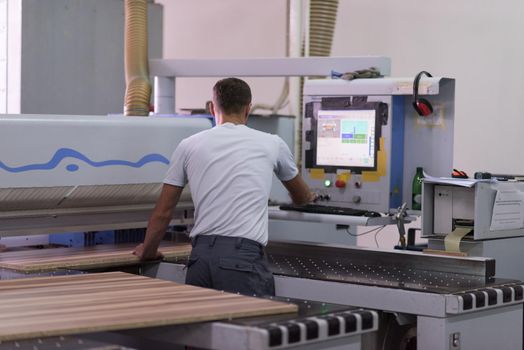 Young worker works in a factory for the production of wooden furniture