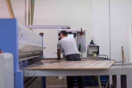 Young worker works in a factory for the production of wooden furniture