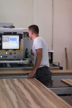 Young worker works in a factory for the production of wooden furniture