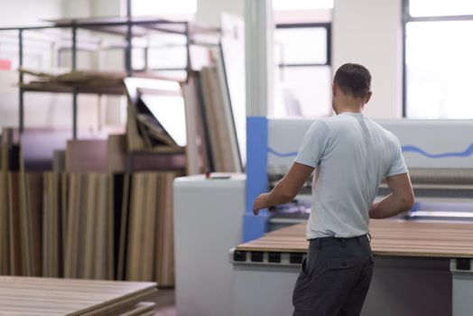 Young worker works in a factory for the production of wooden furniture