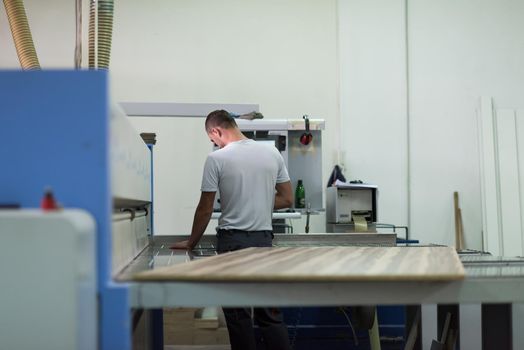 Young worker works in a factory for the production of wooden furniture