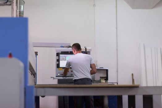 Young worker works in a factory for the production of wooden furniture