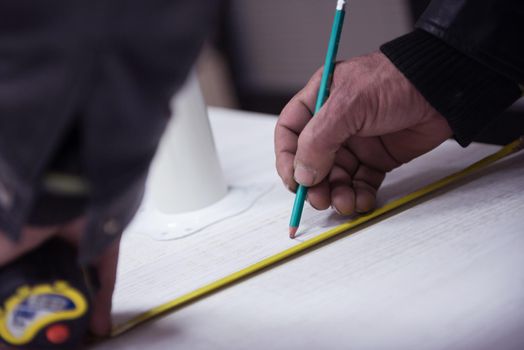 carpenter worker measuring distance for drilling holes in new furniture