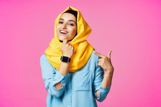 woman wearing yellow hijab electronic watch technology pink background. High quality photo