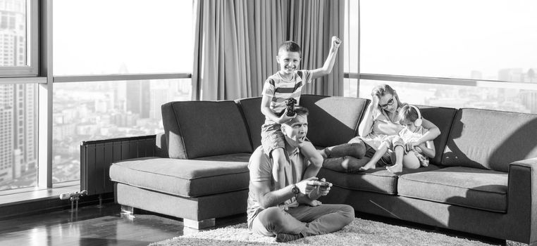 Happy family. Father, mother and children playing a video game Father and son playing video games together on the floor