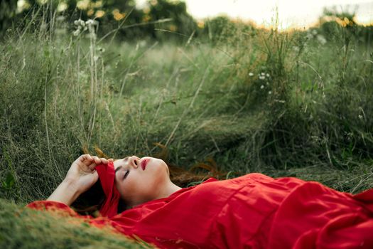 woman in red dress lying on the grass fresh air nature romance. High quality photo