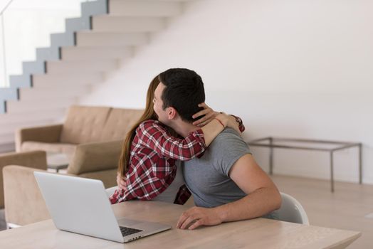 happy young couple buying online using laptop a computer and a credit card in their luxury home villa