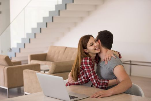 happy young couple buying online using laptop a computer and a credit card in their luxury home villa