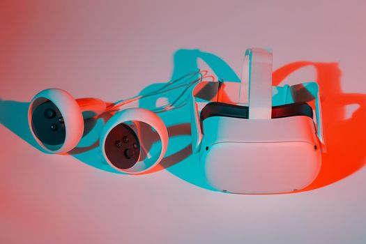 Virtual reality helmet and controllers on white background in neon light. VR, future, gadgets, technology concept.