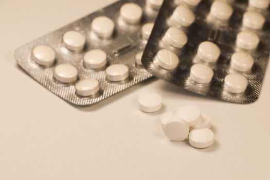 White prescription pills with pill packaging strips close-up abstract on white