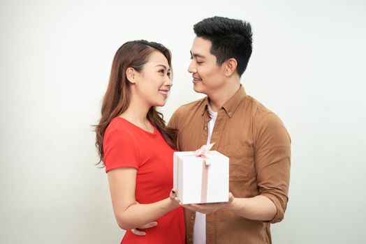 Couple in Valentine Day holding a gift over isolated background hugging