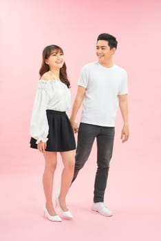 Young emotional man and woman in casual clothes on pink background