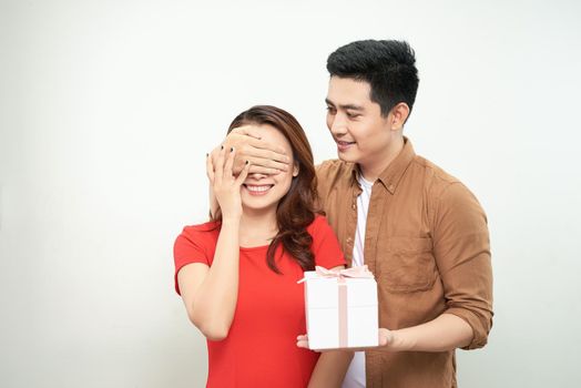 Surprised young couple isolated on white background. Valentine's Day Women's Day, birthday, holiday concept. Hold red present box with gift ribbon bow