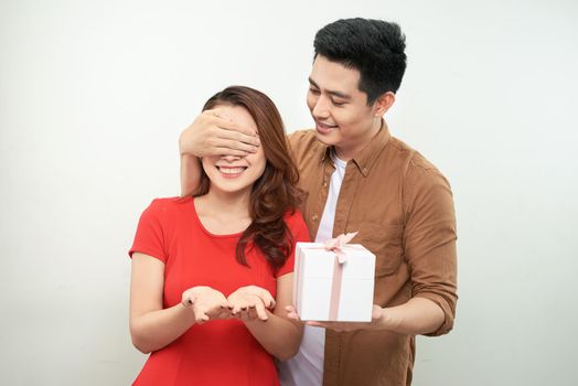 Gift couple holding present closing someone eyes