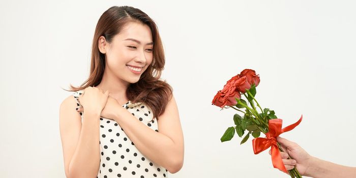 boyfriend presenting bouquet of roses to girlfriend isolated on white