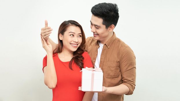 Happy Anniversary, Honey! Attractive asian Man Closing His Woman Eyes, holding gift for her, white background