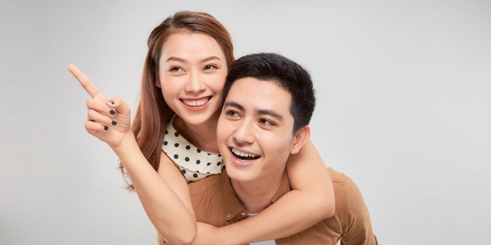 Love forever. Young asian handsome boyfriend is piggybacking his cute lover, wearing casual clothes, on white background
