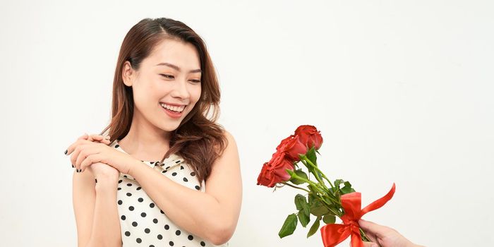 Man giving a bunch of red roses to a surprised woman isolated on white background