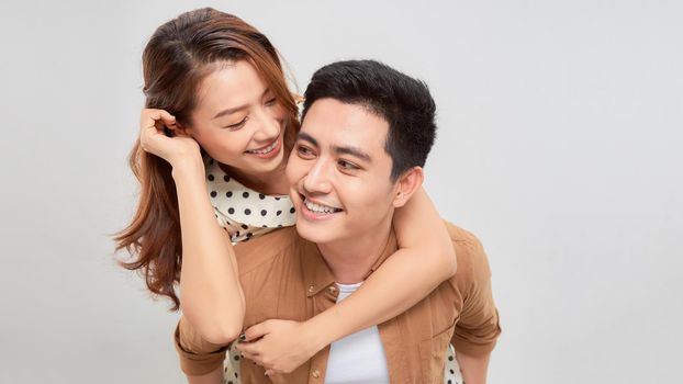 Man giving his pretty girlfriend a piggy back on white background