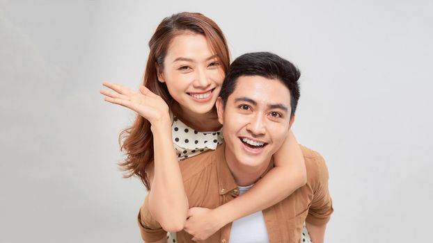 Happy man giving his girlfriend piggy back on white background