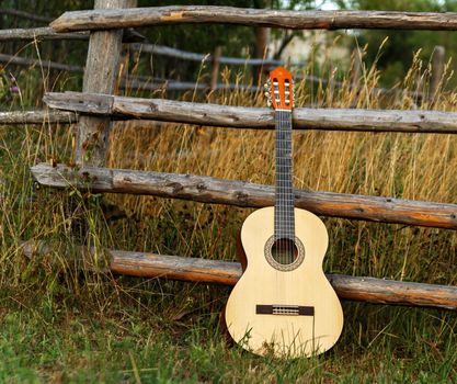 HoHome hobbies. Guitar on background of wooden fence in field, acoustic guitar close-up musical instrument with view from above for recreation or hobby.