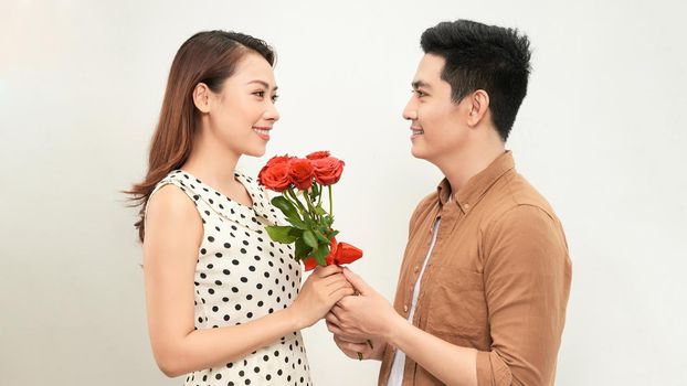 Man giving a bunch of red roses to a surprised woman isolated on white background