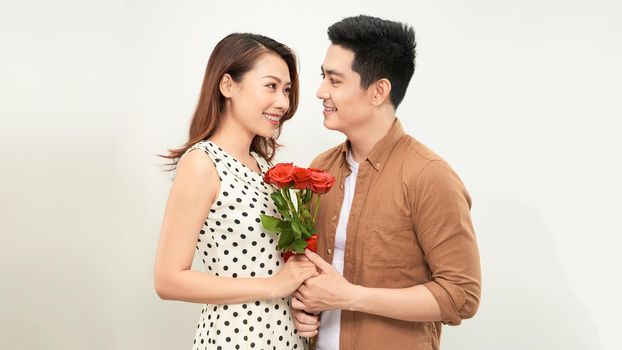 Young beautiful asian couple with flowers isolated on white