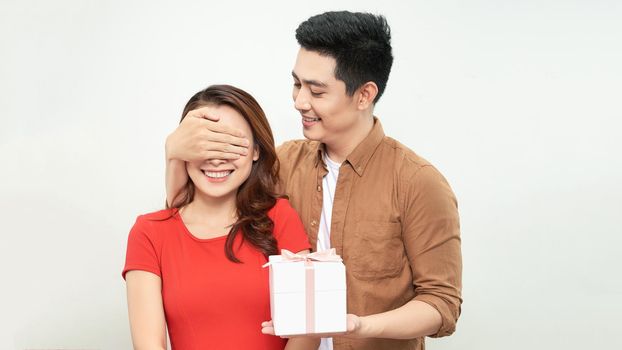 Gift couple holding present closing someone eyes