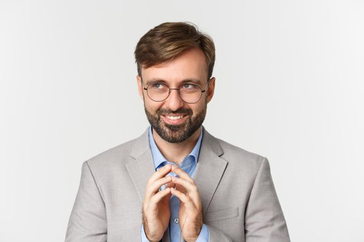 Close-up of thoughtful and devious businessman having an idea, smiling cunning and looking at upper left corner, steeple finers and scheming something, white background.