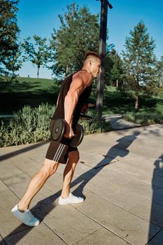 sporty man exercise fitness workout outdoors with dumbbells. High quality photo