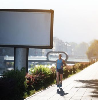 Elderly man jogging down the promenade