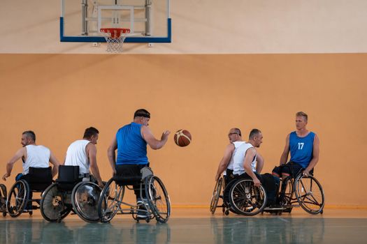 Disabled War veterans mixed race opposing basketball teams in wheelchairs photographed in action while playing an important match in a modern hall. High quality photo