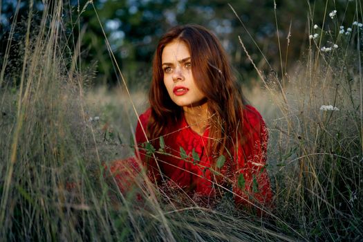 woman in a red dress lies on the grass in the field nature fashion. High quality photo