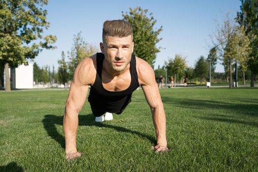 athletic man pumped up body in the park workout fitness fresh air. High quality photo