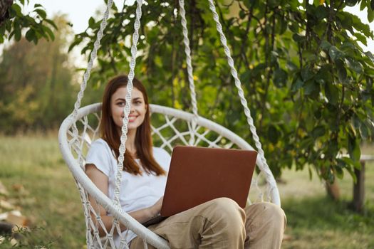 woman with laptop outdoors resting in hammock internet. High quality photo