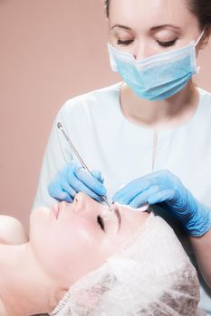 A professional procedure for cleaning the skin with a steel tool for acne and acne in a beauty parlor. Deep cleansing of a woman's face with a blackhead remover in a beauty salon. Beautician receiving cleansing therapy.