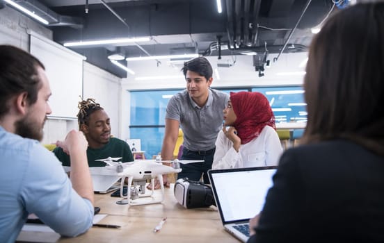 multiethnic startup business team discussing new business plan,working on laptop and tablet computer while learning about drone technology for new business advancement