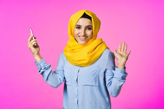 cheerful woman in a yellow hijab with a phone in her hands communication technology. High quality photo