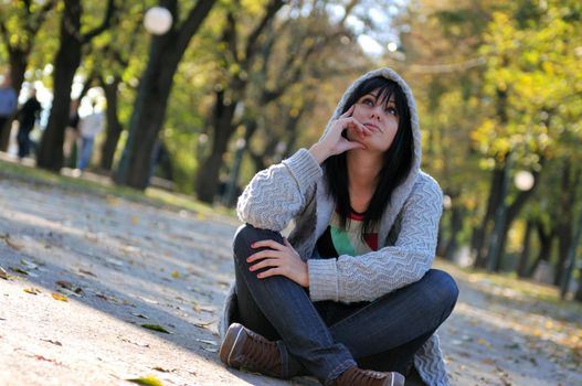 Cute young woman sitting outdoors in nature