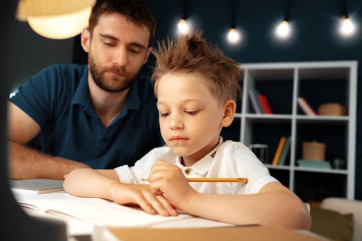 Dad and son doing school homework together sitting at the table